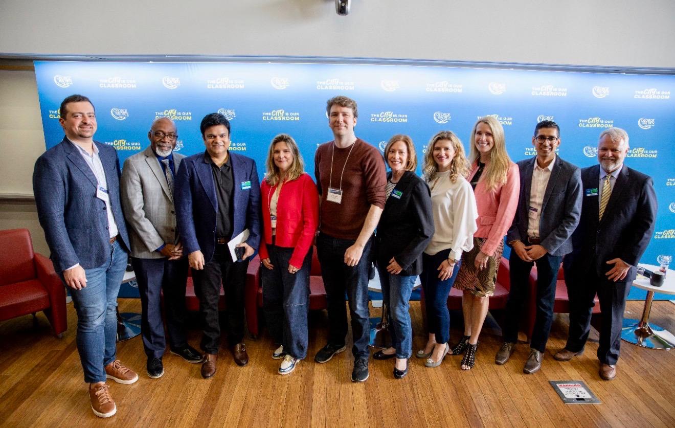 Aakash Andrews with fellow attendees in front of a blue event backdrop