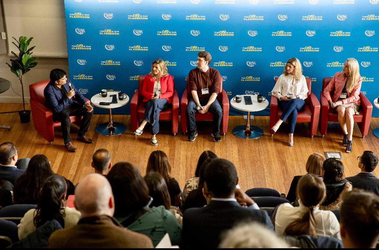 Aakash Andrews moderating a panel discussion before an audience